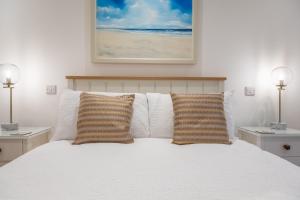 a bedroom with a bed with white sheets and two lamps at Owl Cottage in Great Snoring