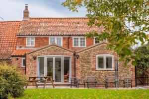 a brick house with a patio in front of it at Owl Cottage in Great Snoring