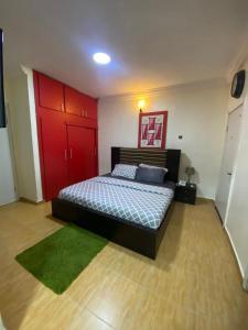 a bedroom with a bed with a red door and a green rug at Studio C, (Studio Apartment) Hillside Gardens in Lagos