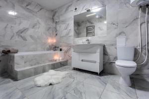a white bathroom with a sink and a toilet and a tub at Viktoria Garden apartment in Lviv