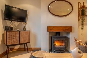 a living room with a fireplace and a television at Maurice Cottage in Docking