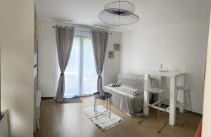 Cette chambre blanche comprend un lit, une table et des chaises. dans l'établissement Le jardin de Broceliande, à Ploërmel