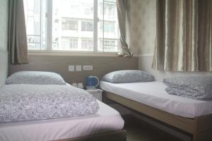 two beds in a room with two windows at K & B Hostel in Hong Kong