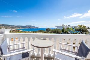balcón con mesa, sillas y vistas al océano en Enalia Suites en Amoopi