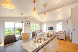 a kitchen with a sink and a living room at Ingol Lodge 2 in Ingoldisthorpe