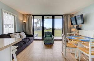 a living room with a couch and a table at 0101 Coastal Retreat by Atlantic Towers in Carolina Beach +17 photos