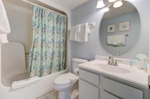 a bathroom with a toilet and a sink and a mirror at 0101 Coastal Retreat by Atlantic Towers in Carolina Beach