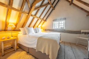 a bedroom with a bed with white sheets and a window at The Beekeepers Cottage in Barney
