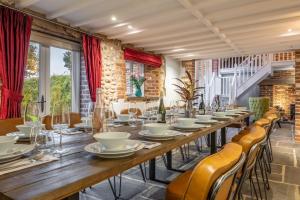 una larga mesa de madera en una habitación con sillas y ventanas en Primrose Farm Barn 14, en Roughton