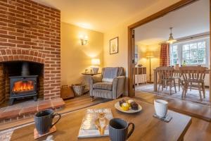 uma sala de estar com uma lareira de tijolos e uma mesa em Sandpiper Lodge em Little Walsingham