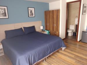 a bedroom with a blue bed and a bathroom at Hotel Boutique Quinta Camacho in Bogotá