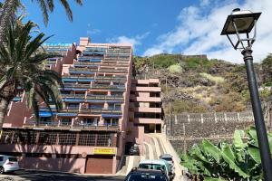 un alto edificio rosa con macchine parcheggiate di fronte di Apartamento La Playa , Los Cancajos La Palma a Los Cancajos