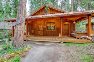 une cabine dans les bois avec une grande terrasse en bois dans l'établissement Enchanting Creekside Cabin Near Kings Canyon Park!, à Badger