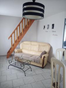 a living room with a couch and a staircase at LE CHANT DES OISEAUX arrivée autonome in Sorbais