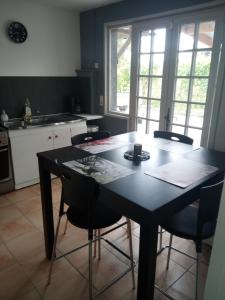 a kitchen with a black table and chairs in it at LE CHANT DES OISEAUX arrivée autonome in Sorbais