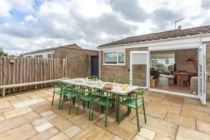 a patio with a table and green chairs at Marsh Tide 4 in Brancaster