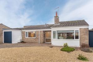 een stenen huis met een witte garage bij Marsh Tide 4 in Brancaster