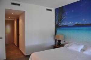 1 dormitorio con un mural en la pared de una playa en Les Suites Golf Bonmont, en Bonmont Terres Noves