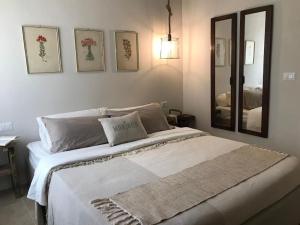 Schlafzimmer mit einem großen weißen Bett und einem Spiegel in der Unterkunft MARIREU in Castiadas