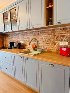 a kitchen with white cabinets and a brick wall at Brand new, feel at home residence in Timişoara