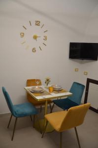 a table and chairs with a clock on the wall at La maison de Rose in Ostuni
