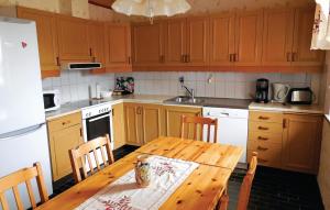 シムリスハムンにあるNice Home In Simrishamn With Kitchenのキッチン(木製テーブル、椅子、冷蔵庫付)