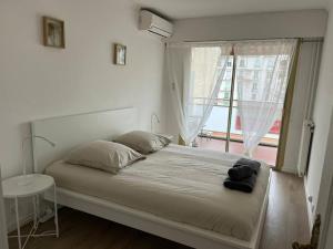a bedroom with a large bed with a window at Superbe T3 L’Illiade - Plages 3’ à pieds - Parking in Juan-les-Pins