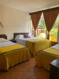 een hotelkamer met drie bedden met gele dekens bij Hotel Posada Don Valentino in Antigua Guatemala