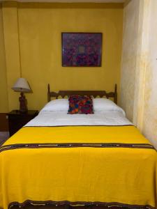 een gele slaapkamer met een groot bed en een gele deken bij Hotel Posada Don Valentino in Antigua Guatemala