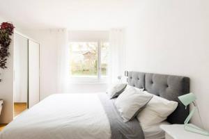 ein weißes Schlafzimmer mit einem großen Bett und einem Fenster in der Unterkunft Apartment of 52 sqm with free parking in Lausanne