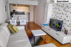 a living room with a white couch and a tv at Apartments FANTASY in Ohrid