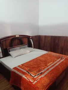 1 dormitorio con 1 cama con cabecero de madera en OYO 81031 Golden Hotel And Restaurant, en Muzaffarnagar