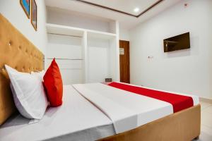 um quarto com uma cama com almofadas vermelhas e brancas em Flagship Hotel Cozy Comfort em Ludhiana