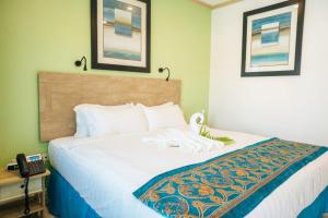 a bed in a hotel room with a phone on a table at Maxwell Del Mar Hotel in Christ Church