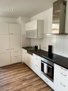 a kitchen with white cabinets and black counter tops at Penthouse im Zentrum von Bregenz in Bregenz