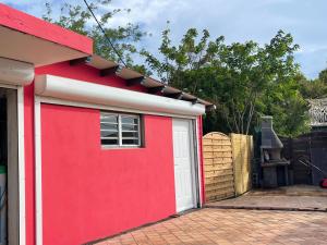 un garaje rojo con una puerta blanca y una valla en Kazabasté, escapade spa et jardin privatif, en Basse-Terre