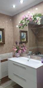 łazienka z umywalką i kwiatami na ścianie w obiekcie Mar Vista w Sant Antoni de Calonge