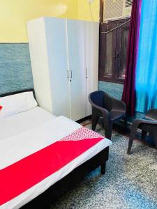 um quarto com uma cama, 2 cadeiras e um armário em OYO 81022 Hotel Haweli em Noida