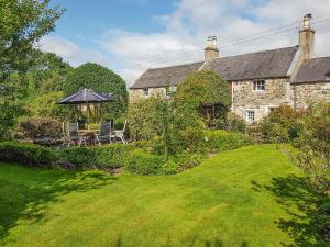 a garden with a table and an umbrella at Bread Oven Cottage in Smailholm