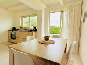 eine Küche mit einem Holztisch und weißen Stühlen in der Unterkunft Plemmirio Apartment in Syrakus