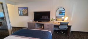 1 dormitorio con escritorio, TV y cama en Dow Villa Motel en Lone Pine