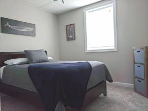 um quarto com uma cama com um cobertor azul e uma janela em The Magnolia Suite At Hilltop Acres - Clarksville em Clarksville