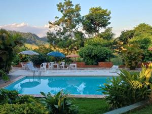 a swimming pool in a yard with chairs and umbrellas at Pousada das Estrelas in Areal