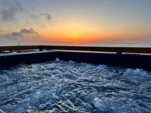 a hot tub with the sunset in the background at Sunset Paradise Oia in Oia