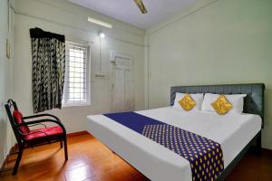 a bedroom with a bed and a red chair at SPOT ON 81127 Ka Lodge in Muttam