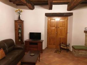 a living room with a couch and a television at Casa in Borgo Medievale in Toscana in Monterone