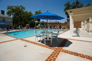 uma piscina com uma mesa e um guarda-chuva azul em Williamsburg Lodge, Autograph Collection em Williamsburg