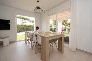 une salle à manger avec une table en bois et des chaises blanches dans l'établissement Villa Alemania Chalet Independiente con Piscina en Urbanización Roche Conil Cádiz Andalucía España, à Roche