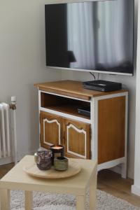 - une télévision sur un support en bois avec une table dans l'établissement La maison du bienvenu, à Namur