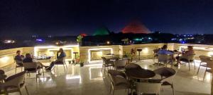Pyramids kingdom - guest house في القاهرة: مجموعة من الناس يجلسون على الطاولات على السطح في الليل